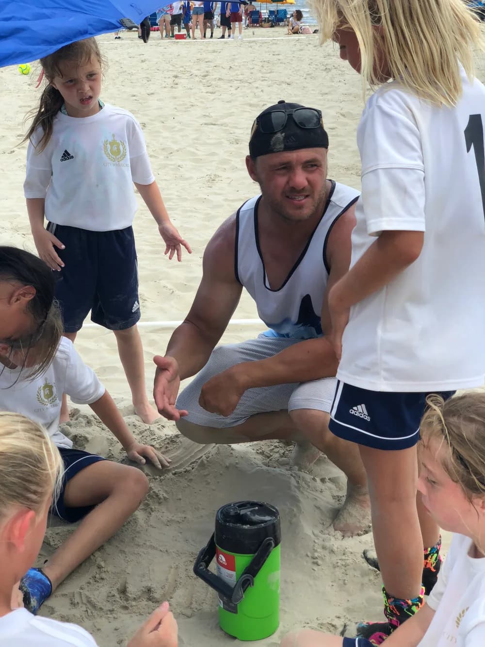 Coach talking with young players during a beach soccer huddle